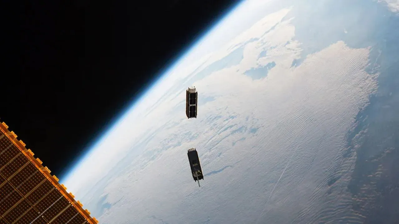 Un par de cubesats instantes después de ser liberados desde un pequeño dispositivo de despliegue de satélites situado en el exterior del módulo experimental Kibo.